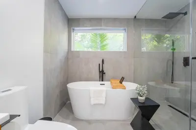 a white bathroom with a tub and a window at 5BR HotTubPoolTableMiniGolf 7 min to Wynwood in Miami