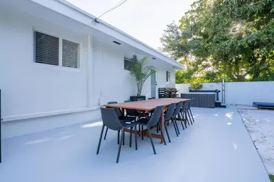 a patio with a wooden table and chairs at 5BR HotTubPoolTableMiniGolf 7 min to Wynwood in Miami
