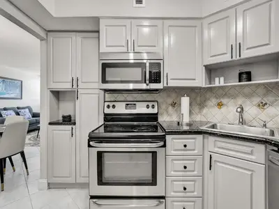 a kitchen with white cabinets and a stove and microwave at Cozy Beachfront 2 Bedroom Condo Beach Service 406 in Miami Beach