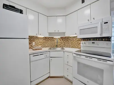a white kitchen with white appliances and white cabinets at Cozy Beachfront 2 BDR Miami Beach Condo 1516 in Miami Beach