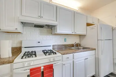 a kitchen with white cabinets and a stove and a sink at Near Haulover Park Hollywood Cottage with Yard! in Hollywood