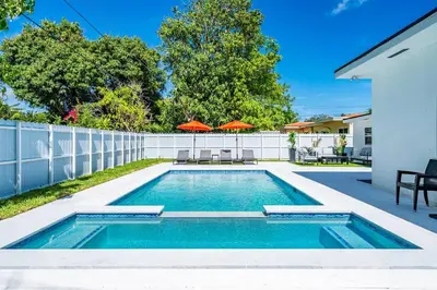 a swimming pool with two umbrellas in a backyard at Stylish 4 Bedroom Home with Pool, 12 Minutes to the beach in Miami