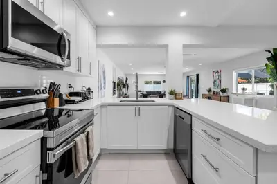 a large white kitchen with white cabinets and appliances at Stylish 4 Bedroom Home with Pool, 12 Minutes to the beach in Miami