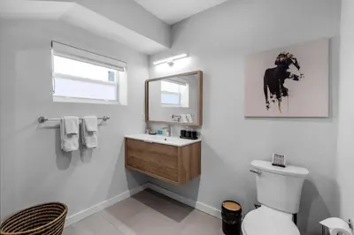 a bathroom with a toilet and a sink and a mirror at Stylish 4 Bedroom Home with Pool, 12 Minutes to the beach in Miami