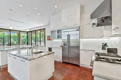 a kitchen with white cabinets and a stainless steel refrigerator at Victoria Villa - Walk to Las Olas - 4 Bed 4 Bath in Fort Lauderdale