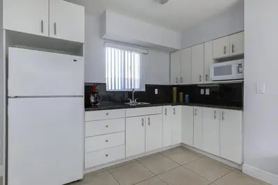 a white kitchen with white cabinets and a window at Hollywood Broadwalk Oceanside Hotel in Hollywood