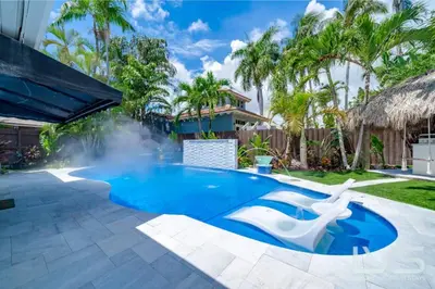 a swimming pool with a fountain in a yard at Floridita 5Bed 4Bath FTL Paradise with Tiki Hut Heated Pool in Fort Lauderdale