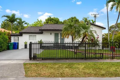 a white house with a black fence and palm trees at D'Mauchi House in Miami