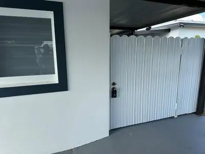 a white fence next to a white wall with a picture at Adrien Guest Studio in Miami Gardens