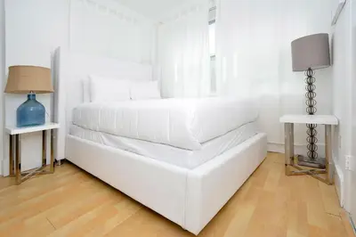 a white bedroom with a white bed and a window at Art Deco Washingthon Apartment in Miami Beach