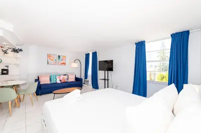 a bedroom with blue curtains and a couch at Art Deco Washingthon Apartment in Miami Beach