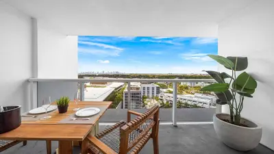 a dining table on a balcony with a view of a city at Luxurious Private Condo at 1 Hotel & Homes - 1545 in Miami Beach