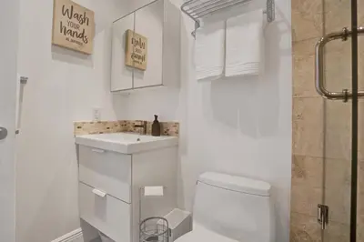 a white bathroom with a toilet and a sink at Casa Coral with Pool Charcoal BBQ area in Miami
