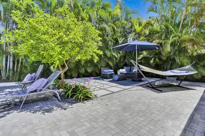 a patio with two chairs and a hammock and an umbrella at Casa Coral with Pool Charcoal BBQ area in Miami
