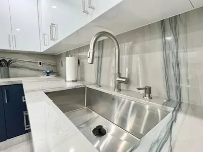 a stainless steel sink in a kitchen with white cabinets at Renovated Grand Villa Paradise Amazing pool, BBQ & Ping Pong in Tamiami