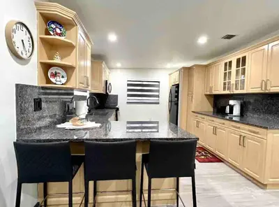 a kitchen with a counter with chairs and a clock at Renovated Grand Villa Paradise Amazing pool, BBQ & Ping Pong in Tamiami