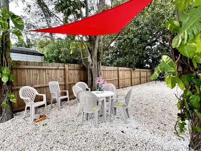 a patio with a table and chairs and a red umbrella at Sunny Resort Oasis with Heated Pool Ping Pong in Tamiami