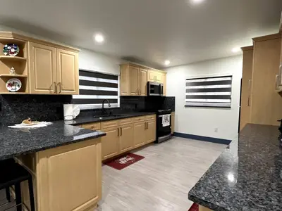 a kitchen with wooden cabinets and black counter tops at Sunny Resort Oasis with Heated Pool Ping Pong in Tamiami