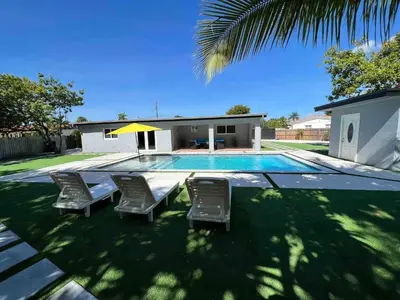 a swimming pool with chairs and a house at Sunny Resort Oasis with Heated Pool Ping Pong in Tamiami