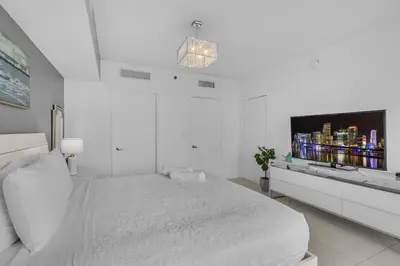 a white bedroom with a bed and a flat screen tv at Lovely 1BR W Icon Brickell-FREE SPA in Miami