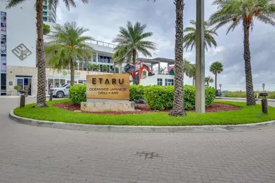 a sign in front of a building with palm trees at Walk to Hollywood Beach Upscale 16th-Floor Condo in Hollywood