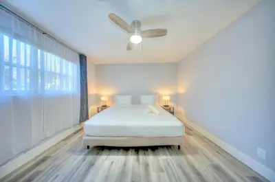 a white bedroom with a bed and a ceiling fan at Mahalo Isles Apartments by Rocketstay in Fort Lauderdale