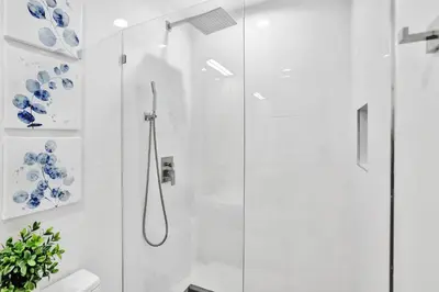 a white bathroom with a shower with a glass door at Modern home w heated pool canal views in Hollywood