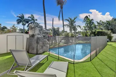a swimming pool in a yard with two chairs at Modern home w heated pool canal views in Hollywood