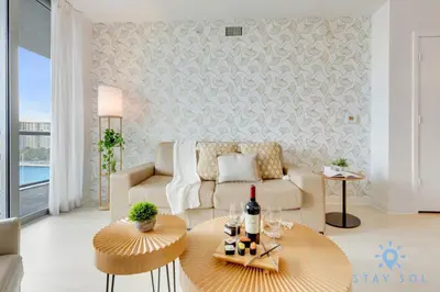 a living room with a couch and a table with wine glasses at Beachwalk Resort Prime Location Balcony Gym in Hallandale Beach