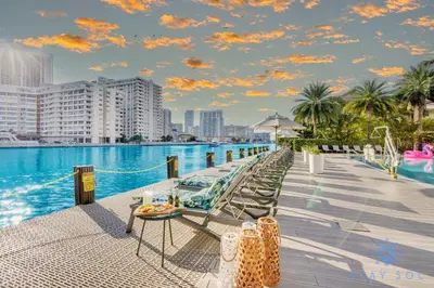 a pool with chairs and a table next to the water at Beachwalk Resort Prime Location Balcony Gym in Hallandale Beach
