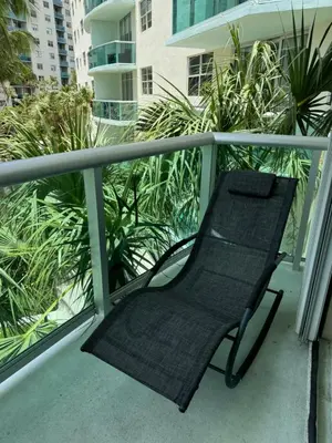 a black chair sitting on a balcony with plants at Tropical ocean view 1 bedroom in Hollywood