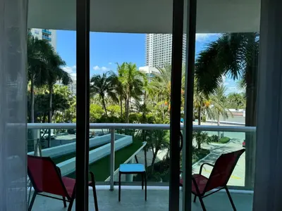 two chairs and a table on a balcony with palm trees at Ocean front 1 bedroom in Tropical Paradise in Hollywood