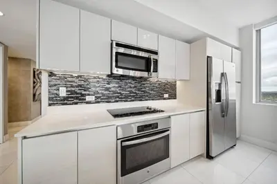 a kitchen with white cabinets and a stainless steel refrigerator at Million Dollar Waterfront Penthouse in Hallandale Beach