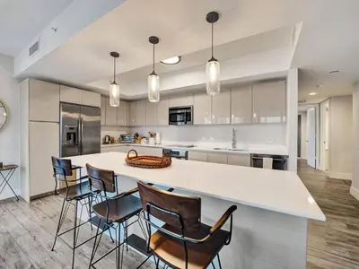 a kitchen with a large white counter and chairs at Luxury Waterfront Suite with Great Views in Hallandale Beach
