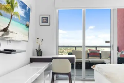 a white living room with a table and a chair at Top Floor Luxury Penthouse with Private Roof Deck in Hallandale Beach