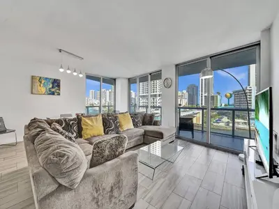 a living room with a couch and a tv at Luxury Waterfront Suite in Hallandale Beach