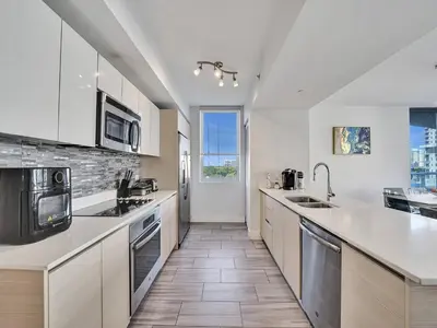 a large kitchen with white counters and a large window at Luxury Waterfront Suite in Hallandale Beach