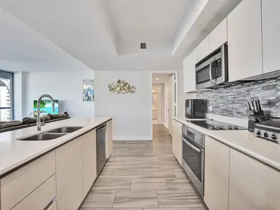 a large kitchen with white cabinets and a tile floor at Luxury Waterfront Suite in Hallandale Beach