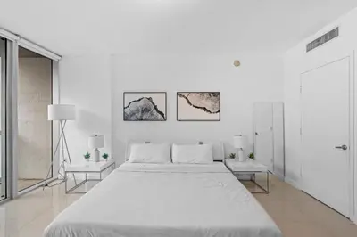 a white bedroom with a large bed and two tables at Studio in Miami Brickell Business District ICON Residences in Miami
