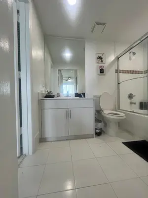 a white bathroom with a toilet and a sink at Enjoy an endless summer - Parking included! in Sunny Isles Beach