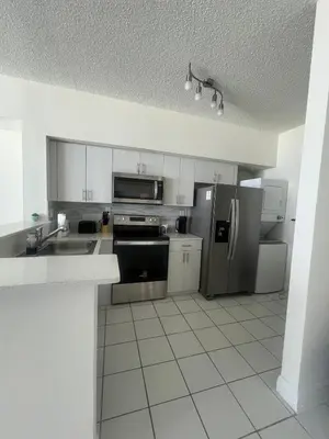 a kitchen with stainless steel appliances and white cabinets at Enjoy an endless summer - Parking included! in Sunny Isles Beach