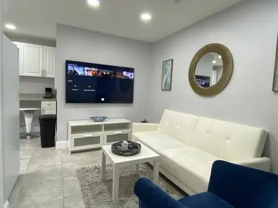 a living room with a white couch and a tv at Annas Peaceful mini Luxury suite in Fort Lauderdale