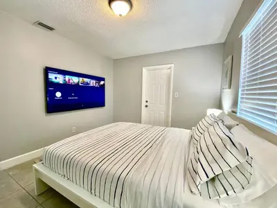 a bedroom with a bed with a tv on the wall at Anna's peaceful Getaway Luxury Suite in Fort Lauderdale