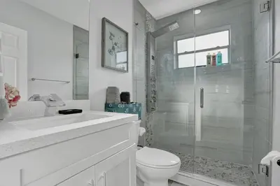 a white bathroom with a shower and a toilet at The Front Wave Luxury Home in Fort Lauderdale