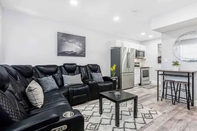 a living room with a black leather couch and a kitchen at Mazor Luxury Two bedroom vacation Home in Fort Lauderdale