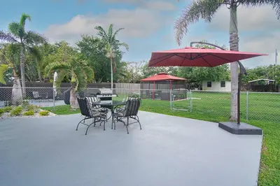 a patio with a table and chairs and a red umbrella at Rachaels Upscale Two Bedrooms Luxury Home in Fort Lauderdale