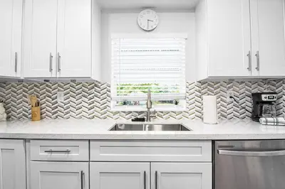 a kitchen with white cabinets and a sink and a window at Rachaels Upscale Two Bedrooms Luxury Home in Fort Lauderdale
