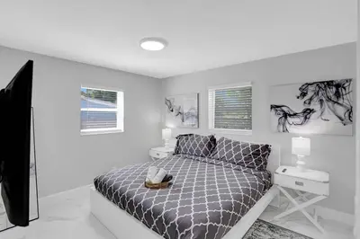 a white bedroom with a bed and a night stand at Yehudas Tropical Villa with Heated Infinity Pool in Hollywood