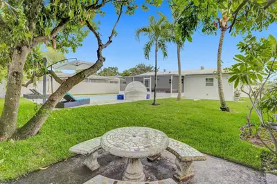 a stone bench in a yard with palm trees at Yehudas Tropical Villa with Heated Infinity Pool in Hollywood