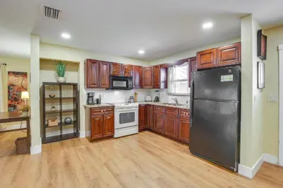 a kitchen with wooden cabinets and a black refrigerator at Spacious House near Fort Lauderdale - Minutes from Beach in Plantation